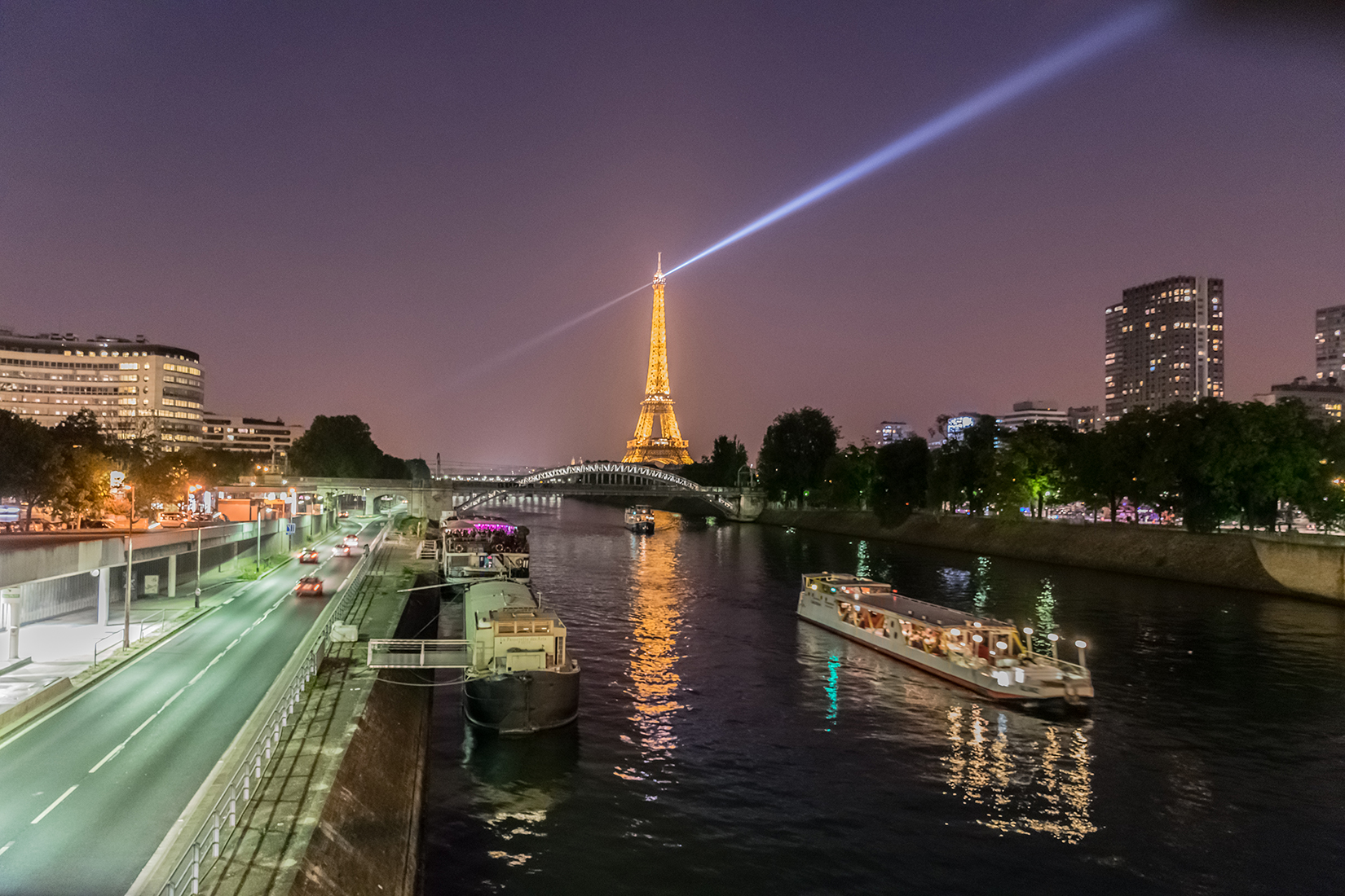 The Eiffel Tower illuminated at night. Here seen from the Pont du Garigliano bridge over the Seine in the west of the city